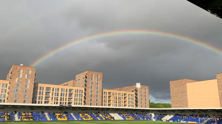 File photo from May 18, 2021: Plough Lane, AFC Wimbledon's ground, on the first match played there with spectators. It does not show this week's member presentation. The cropped 16:9 derivative is offered under the same CC BY-SA 4.0 licence as the original.