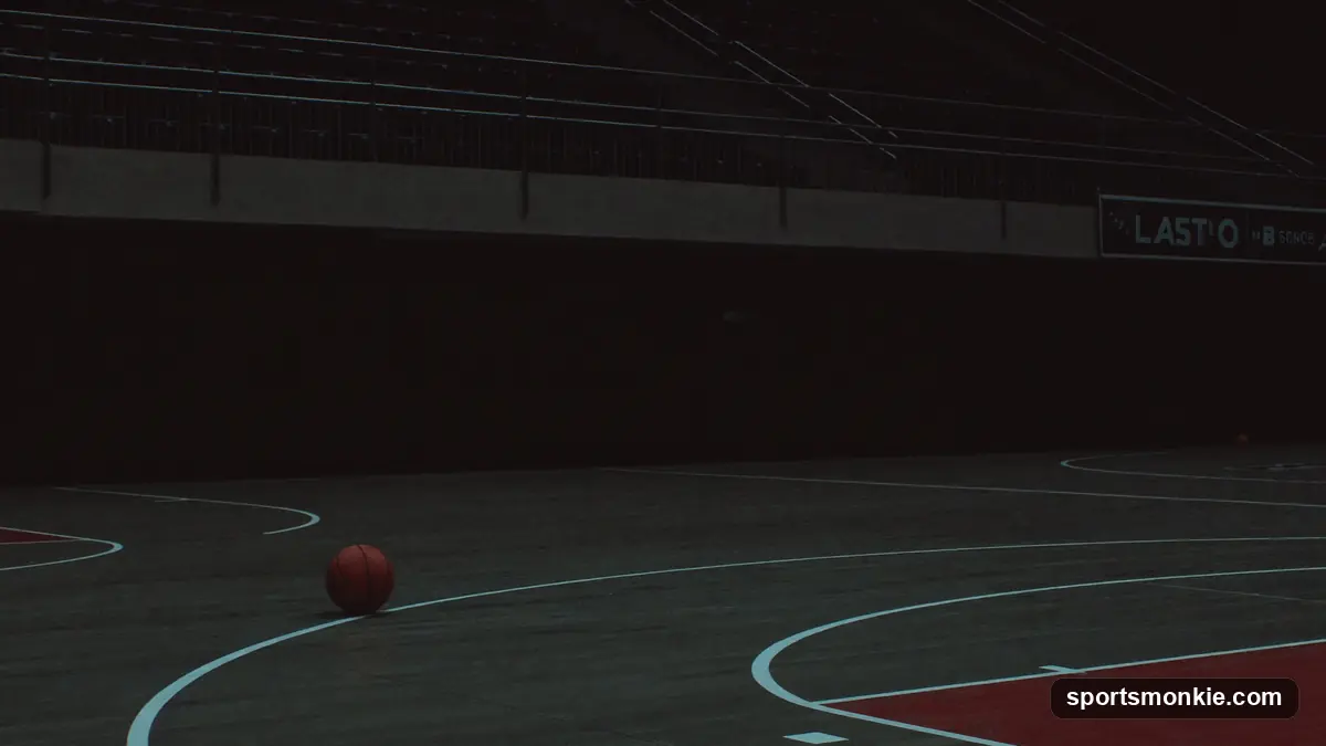 Empty basketball arena seats above a dimly lit court