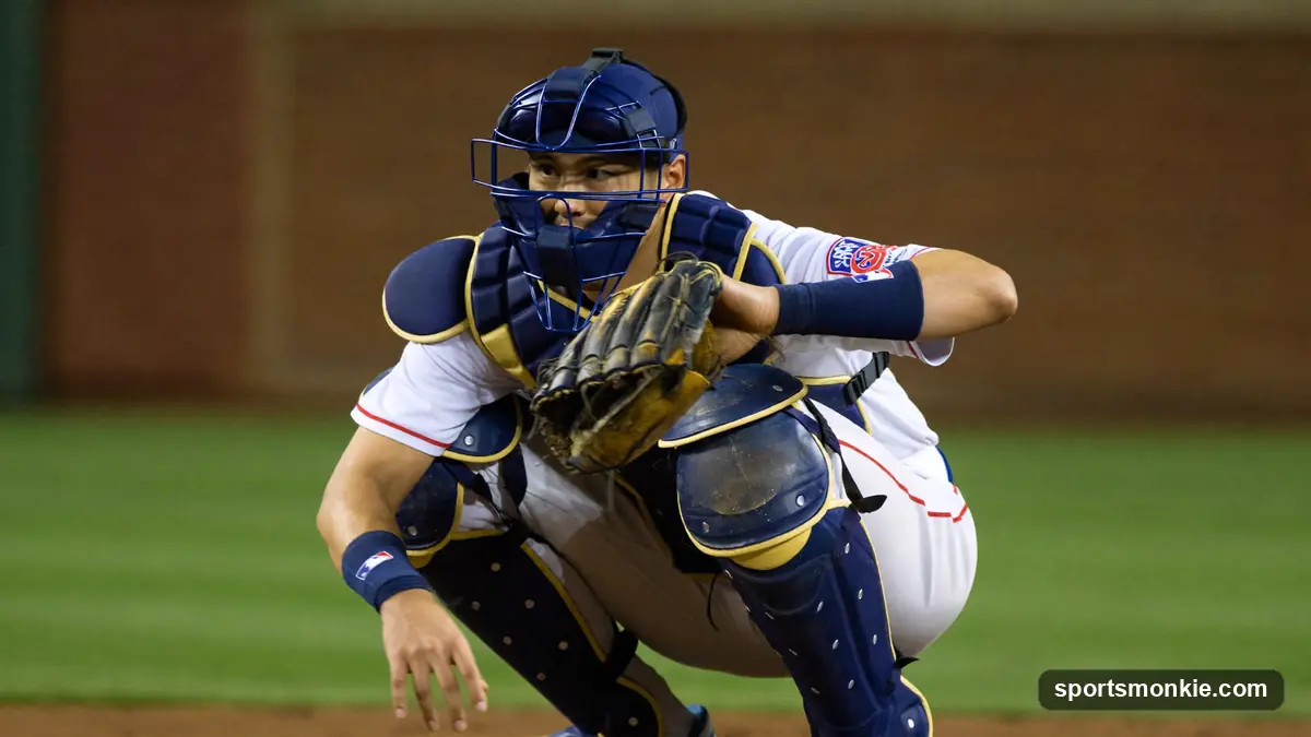 Baseball catcher in full gear crouched behind home plate giving signs