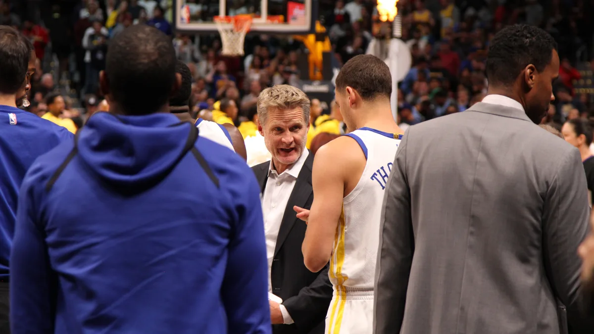 File photo from 4 November 2017: Golden State Warriors head coach Steve Kerr talking to his team before a game in Denver. It does not show the Las Vegas preseason game or Steve Gillis. The 16:9 cropped derivative is offered under the same CC BY-SA 4.0 licence.