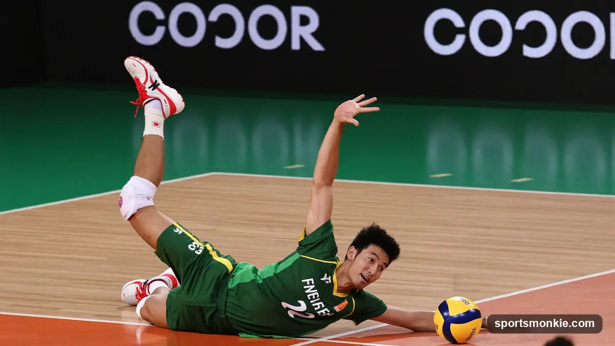 A volleyball defender sliding with one flat hand on the floor as the ball bounces off it